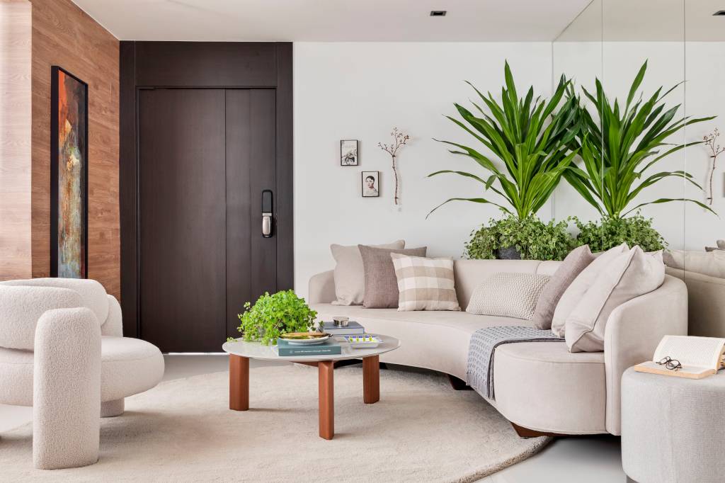 paleta-ancorada-no-preto-ape-painel-ripado-piso-de-porcelanato-rebeca-de-franca-01-sala-plantas Com paleta ancorada no preto, apê tem painel ripado e piso de porcelanato. Projeto de Rebeca de França. Na foto, sala de estar, sofá curvo bege, plantas.
