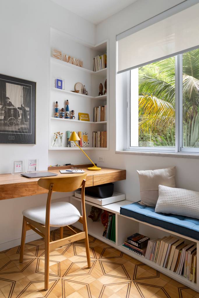 Apê de 102 m² integra acervo de antiguidades dos moradores. Projeto do escritório Maia Romeiro Arquitetura. Na foto, escritório com mesa de trabalho e banco na janela