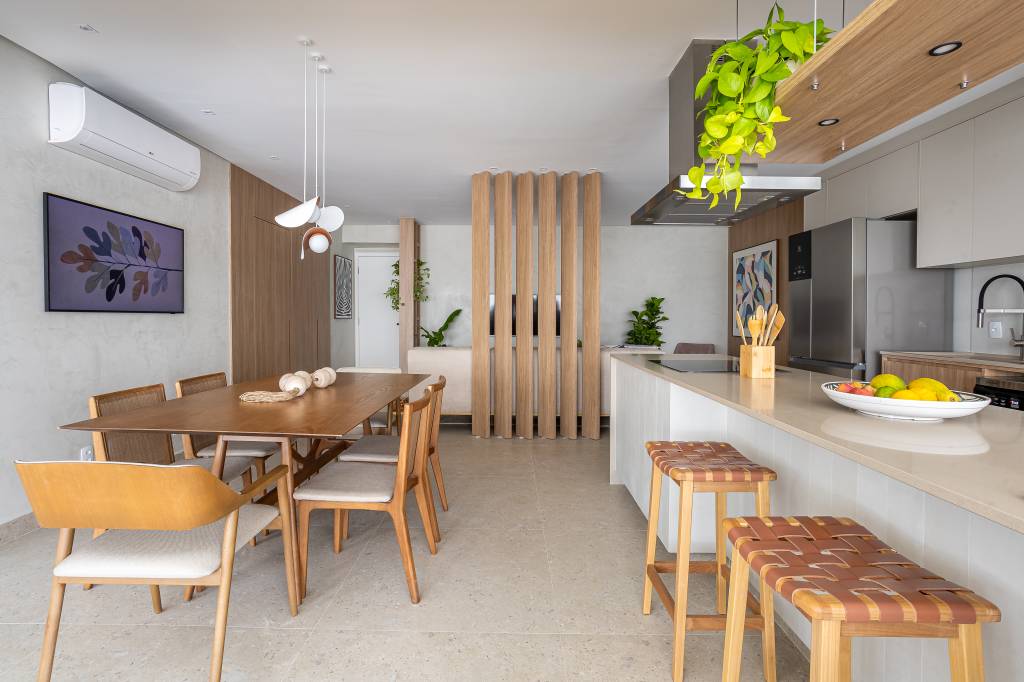 Apê ganha ilha de cozinha espaçosa e brises delimitando sala de TV. Projeto de Go Up Arquitetura. Na foto, sala de tv, jantar e estar integradas.