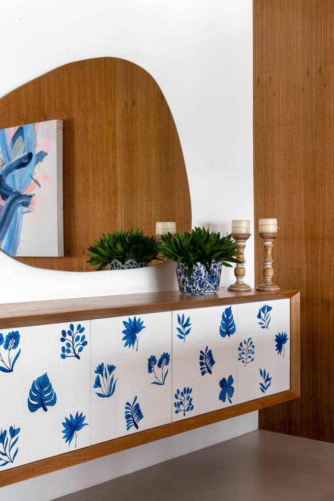 azulejos-pintados-a-mao-revestem-varanda-ape-renata-lemos-01-buffet Azulejos pintados à mão com estampas botânicas revestem varanda de apê. Projeto de Renata Lemos. Na foto, buffet com azulejos, espelho em forma orgânica.