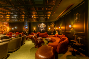 Bar intimista foi inspirado no filme  "O Grande Hotel Budapeste”. Projeto de Rafa Zampini. Na foto, bar com poltronas e sofás de diferentes materiais