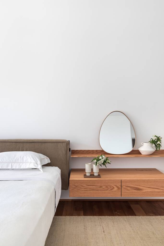 Cobertura deslumbrante de 760 m² na praia tem cozinha gourmet e piscina. Projeto de Simara Melo. Na foto, quarto minimalista branco, cama baixa., espelho.
