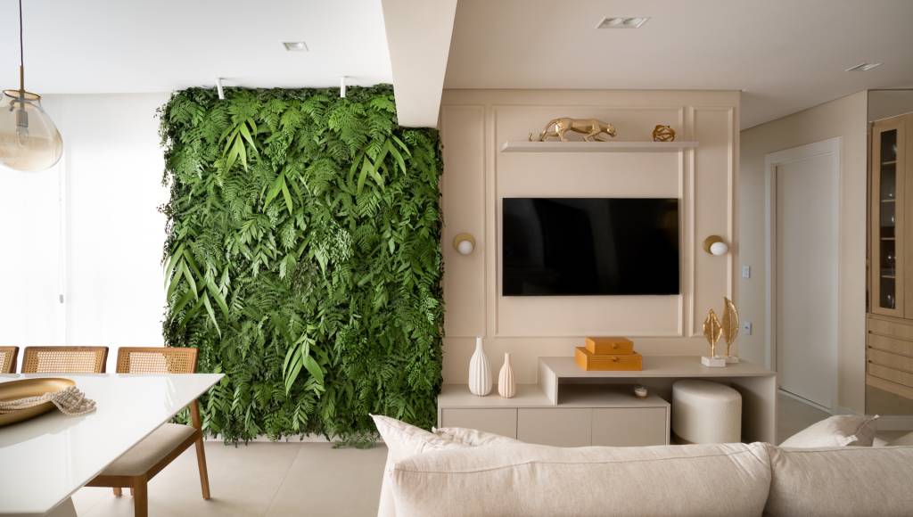 Jardim vertical na sala traz verde para apê com ilha de mármore na cozinha