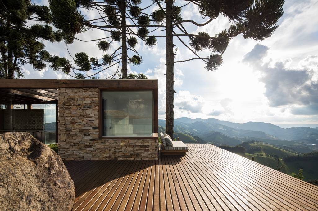 Linda casa na montanha tem lareira e cozinha rústica com fogão à lenha. Projeto de Sabella Arquitetura. Na foto, varanda, deck, vista.