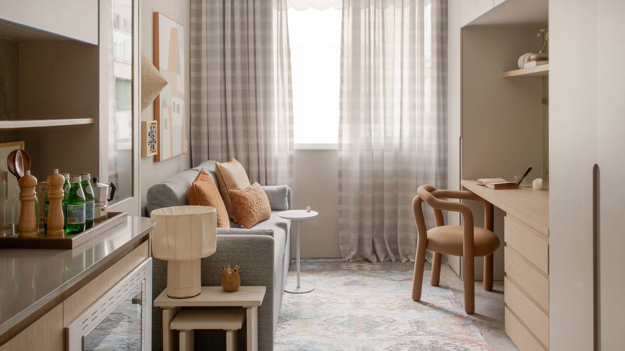 Mini apê japandi de 24 m² tem sofá-cama, lavanderia e formas arredondadas. Projeto de MBV Arquitetura. Na foto, sala de estar, cortina xadrez, sofá com manta.