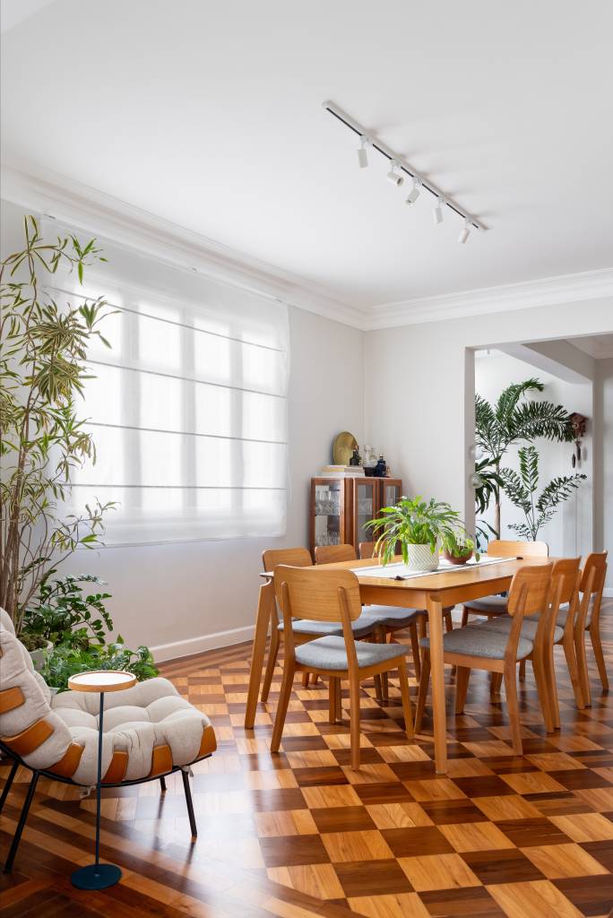 Piso de taco, janelas brancas e sancas dão charme parisiense a este apê. Projeto de Ana Paula Crivelenti. Na foto, sala de estar, mesa grande de madeira.