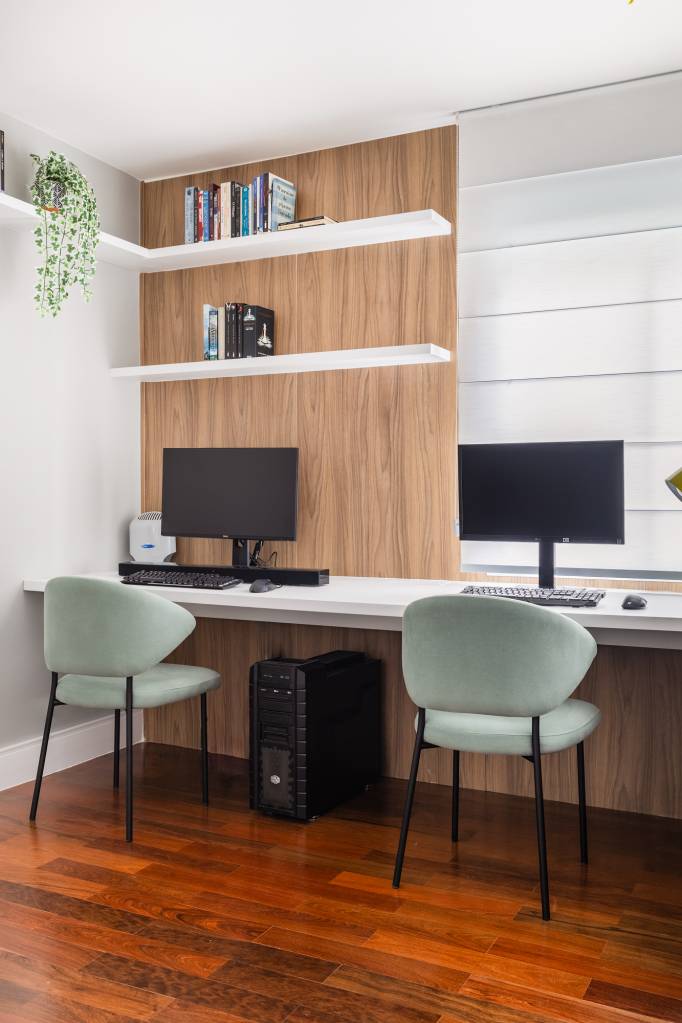 Apê tem cozinha com marcenaria preta e home office com painel ripado branco. Projeto de Duno Arquitetura. Na foto, home office duplo, bancada branca.