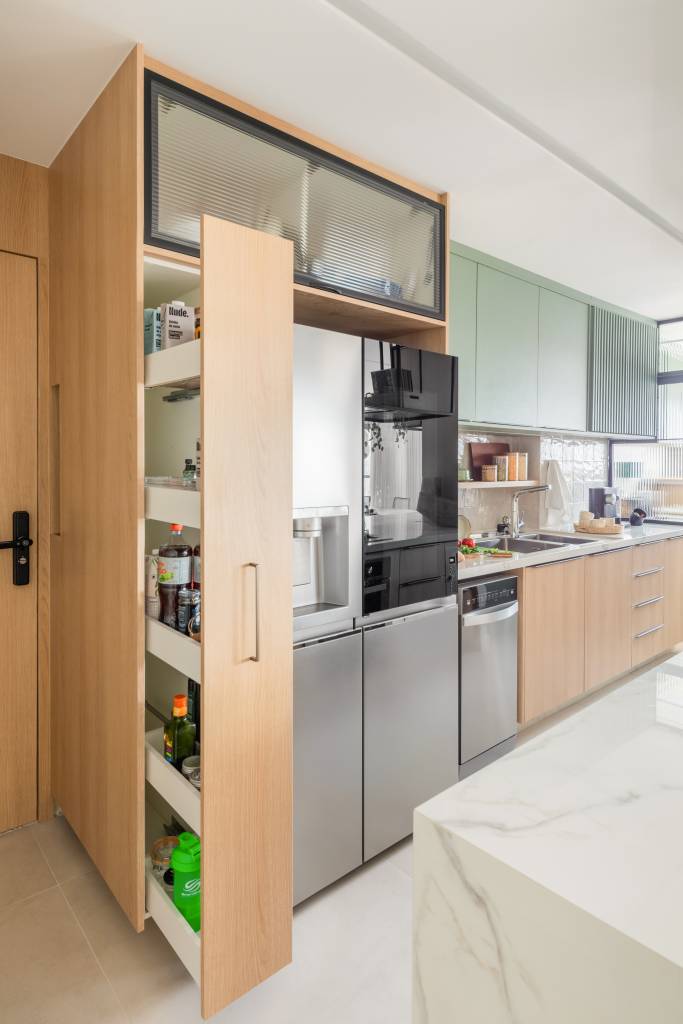 Bancada de lâmina sintetizada integra cozinha e área gourmet neste apartamento. Projeto de BMA Studio. Na foto, marcenaria inteligente na cozinha.