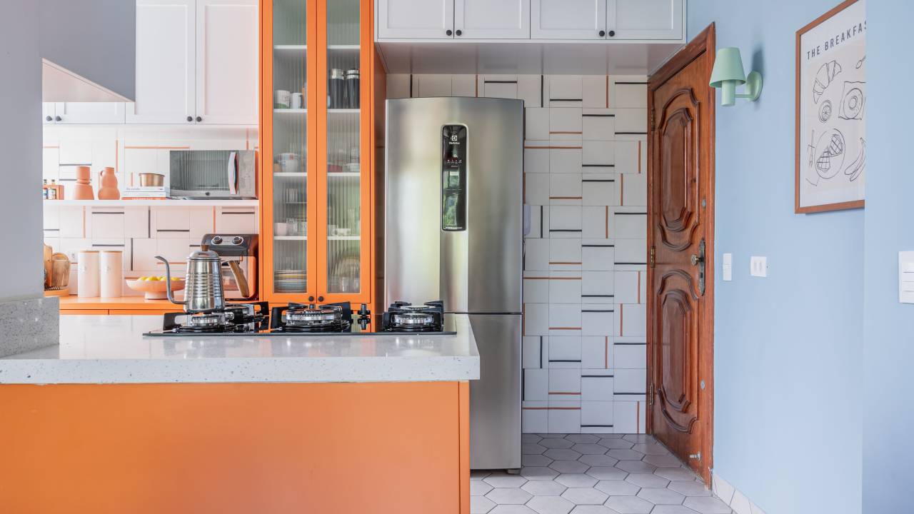 Combinação de laranja, azul e cinza cria cozinha alegre e leve. Projeto de Co+Lab Juntos Arquitetura. Na foto, ilha, cooktop.