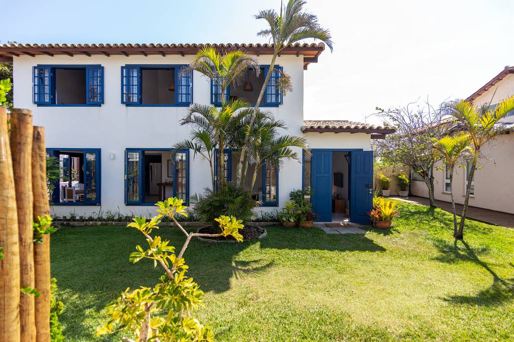 Janelas azuis dão charme a casa de praia em Búzios com suíte térrea escondida por lambris. Projeto de Fernanda Zeitoune. Na foto, fachada, jardim, palmeira.