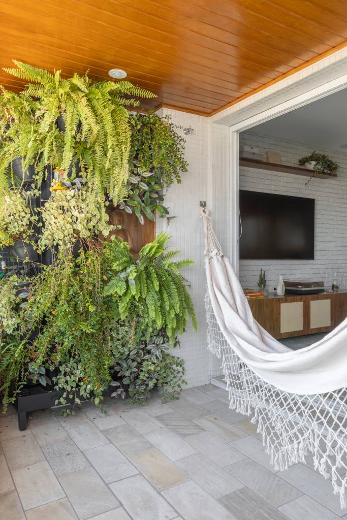 Reforma transforma quarto em home office e o integra a sala com porta de correr verde. Projeto de Adriana Favaro Arquitetura. Na foto, varanda, rede, jardim vertical.