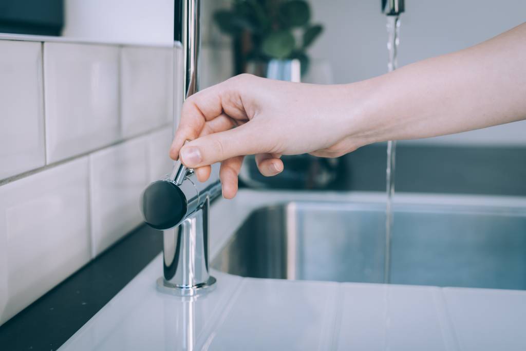 Horizontal shot of a human hand opening the modern sink for the flow of water Torneira pingando? Passo a passo para arrumar sem precisar de encanador