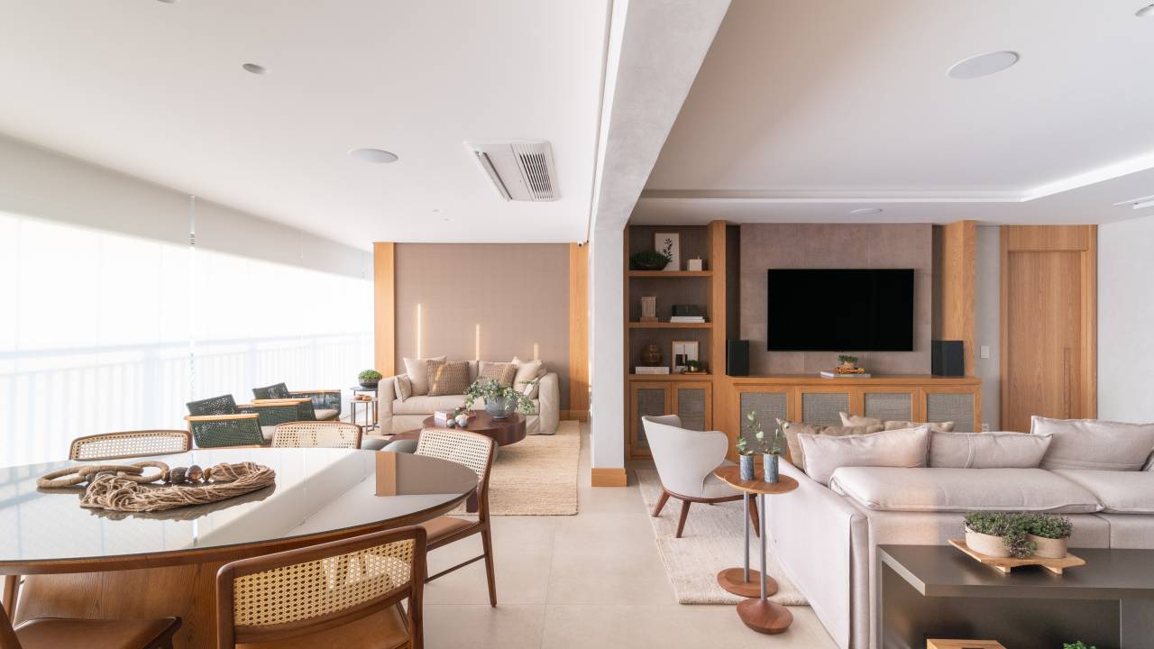 Apartamento ganha varanda gourmet com pequeno living e mesa redonda. Projeto de Andrea Teixeira. Na foto, varanda integrada, mesa redonda, sala de tv.