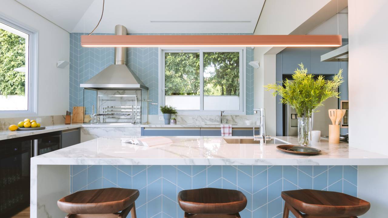 Cozinha azul e beliche em color block são destaque em casa de praia. Projeto de Rawi Arquitetura + Design. Na foto, ilha, churrasqueira.