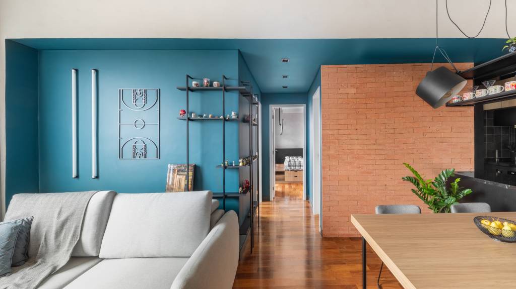 industrial-e-leve-apartamento-combina-serralheria-cores-claras-escuras-studio-ela-09-sala Industrial e leve: apartamento combina serralheria com cores claras e escuras. Projeto de Studio Elã. Na foto, sala, parede azul, estante de serralheria, sofá cinza, tijolinhos.