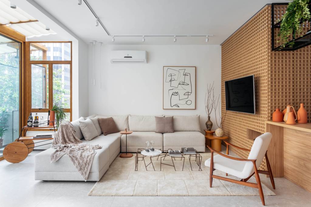 Painéis em muxarabi de MDF delimitam hall e abrigam TV em apartamento de 115 m²