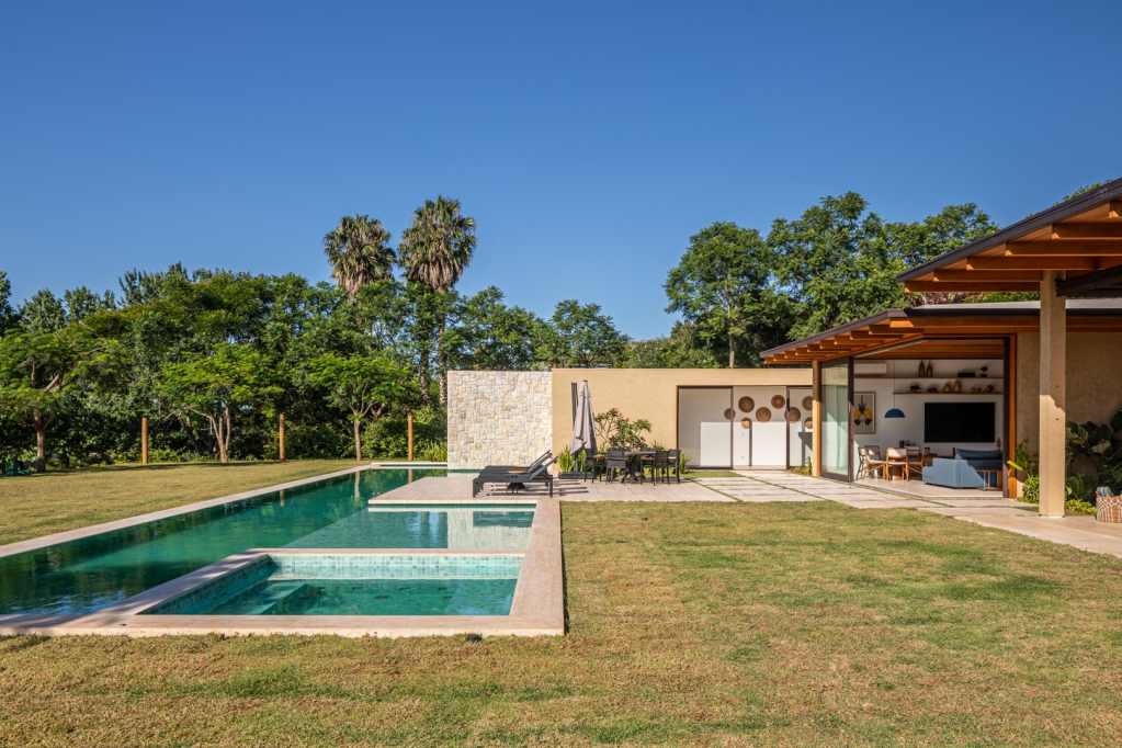 Vidro e brises de madeira conectam casa com 7 suítes com a natureza. Projeto de Gilda Meirelles Arquitetura.