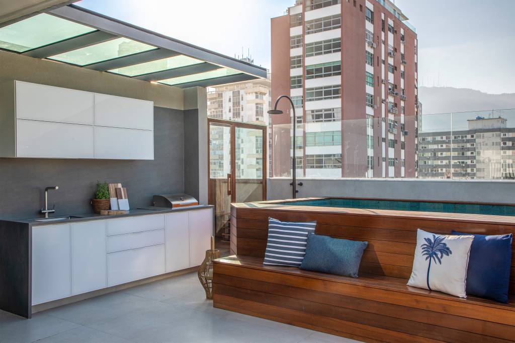 Área de lazer de cobertura ganha cozinha aberta, piscina e banco no deck
