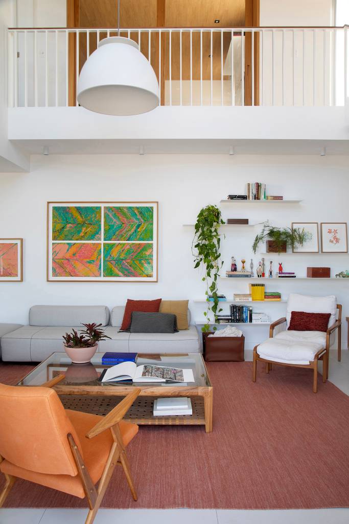 Cozinha aberta e painel de marcenaria em laca verde dão ar leve a cobertura. Projeto de Escala Arquitetura. Na foto, sala de estar, poltrona com pufe, prateleiras, plantas.