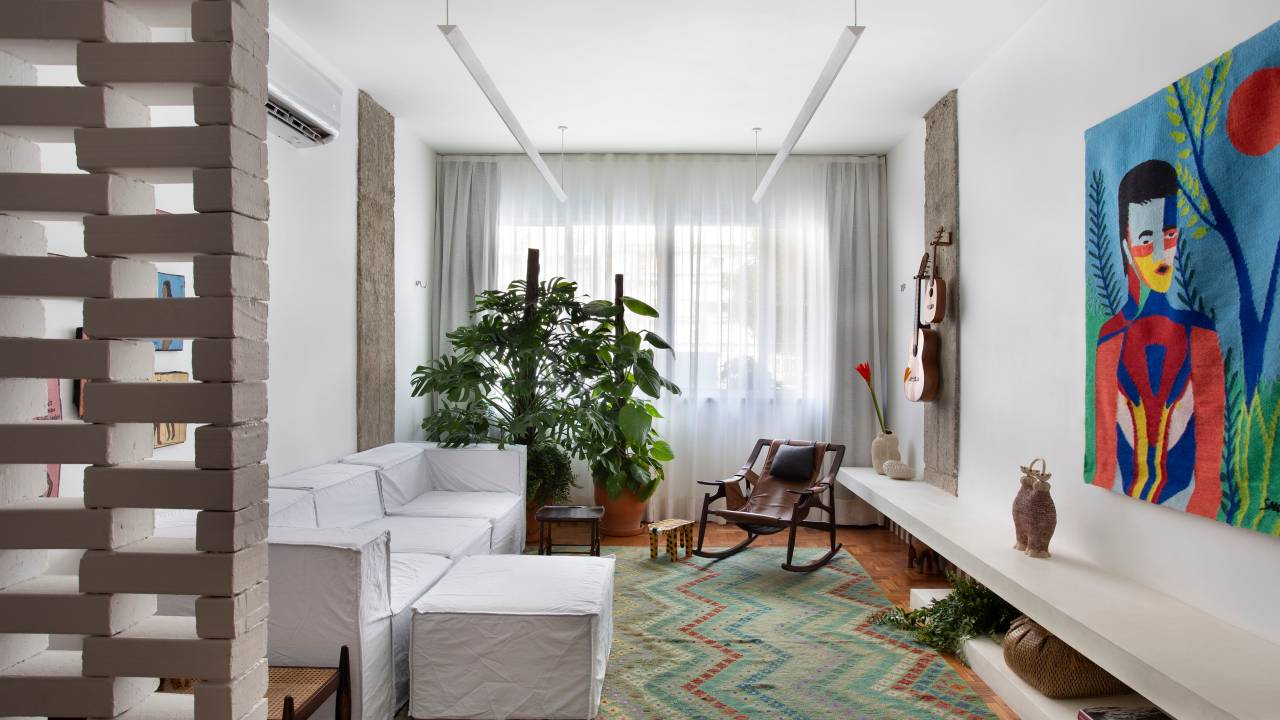 Divisória vazada feita com tijolinhos tem estética de cobogós na sala de apê. Projeto de BRIC Arquitetura.