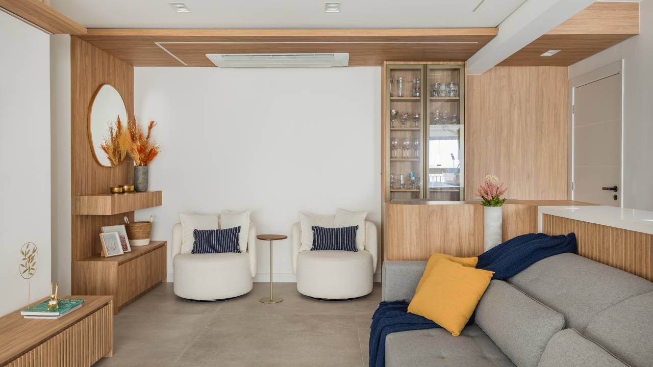 Apê de 116 m² tem guarda-roupa com porta de palinha. Projeto de Katia Guerreiro. Na foto, sala de estar com poltronas, sofá e cristaleira.