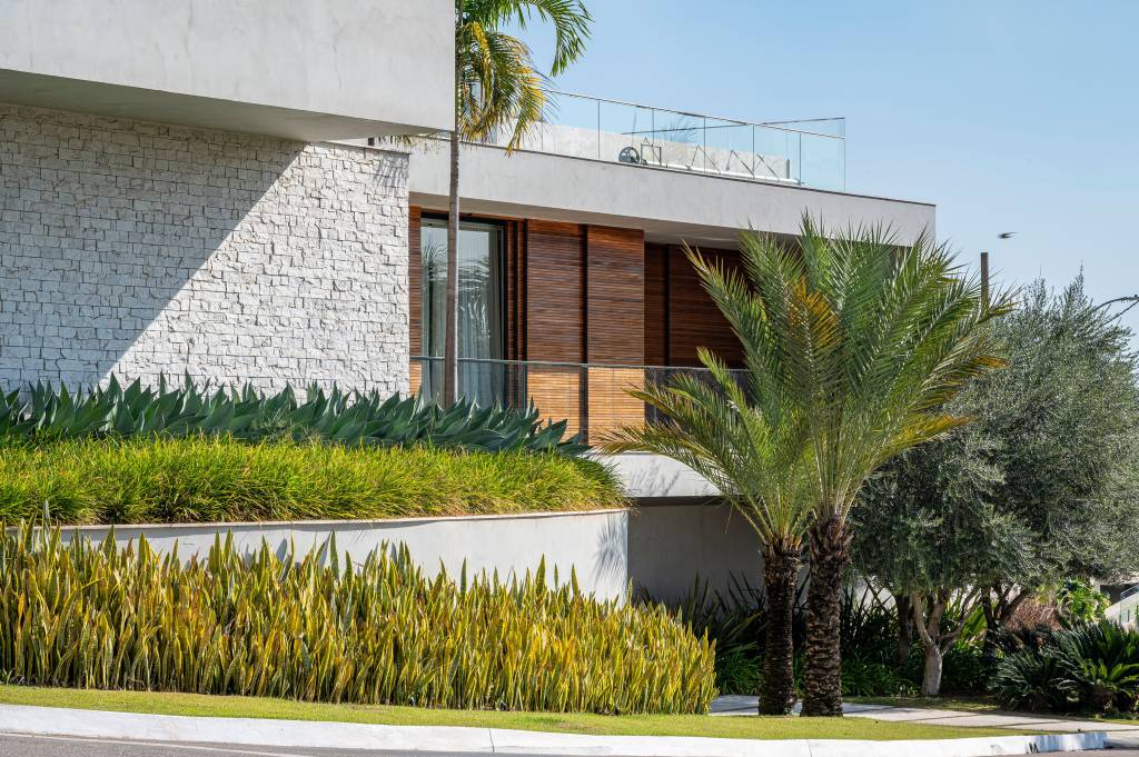 Paisagismo-de-casa-de-860-m2-conta-com-31-especies-diferentes-04 Paisagismo de casa de 860 m² conta com 31 espécies diferentes. No projeto Flávia D’Urso. Na foto, fachada de casa com jardim externo.