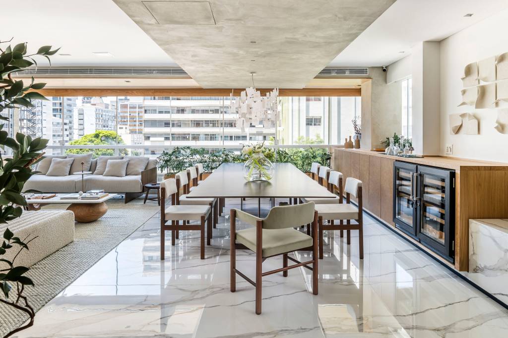 Apê tem piso de porcelanato marmorizado e painel em mármore na cabeceira. Projeto de Liró Arquitetura.