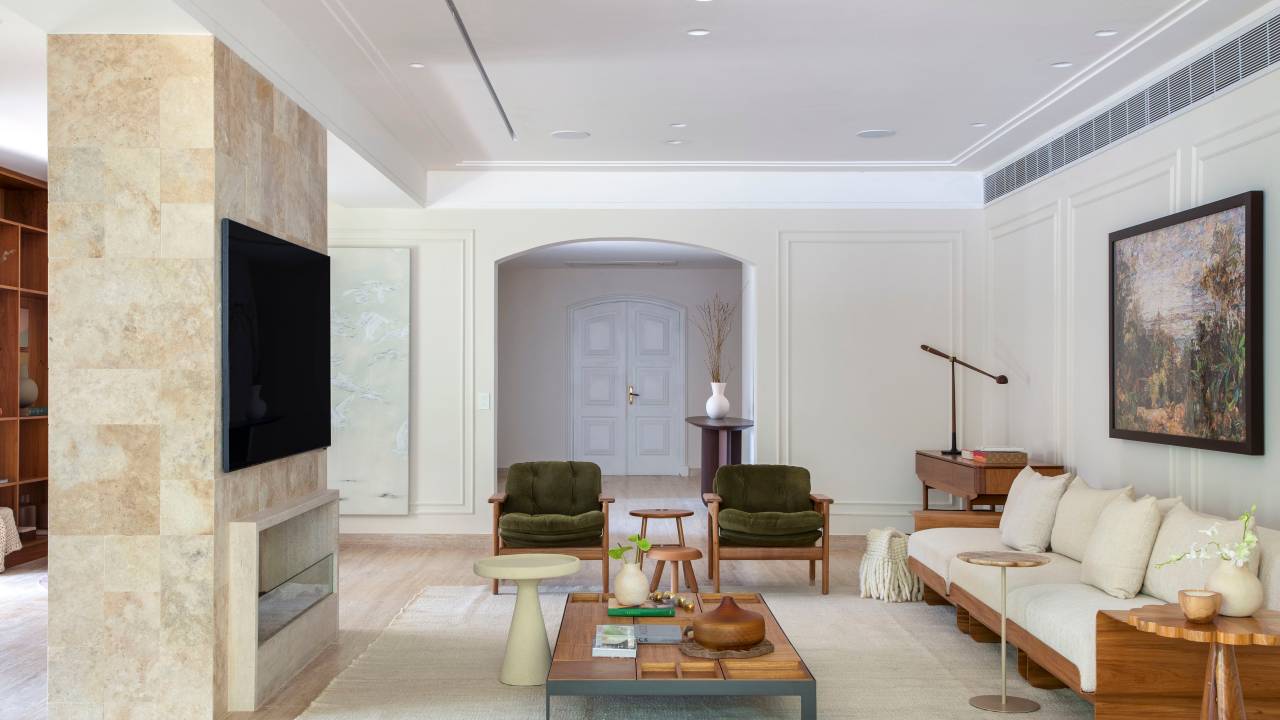 Casa em estilo clássico europeu tem piso mármore e árvore na área gourmet. Projeto de Studio LAK. Na foto, sala de estar, poltrona verde, boiseries.