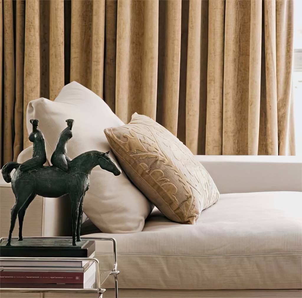 estofado-veludo-elegante-decoracao-moderna A imagem apresenta um elegante estofado revestido em veludo, destacando seu tom rico e textura suave. O ambiente ao redor é decorado de maneira contemporânea, com um toque de requinte que complementa perfeitamente o mobiliário. Há elementos decorativos que refletem a luz, realçando a beleza do veludo e criando uma atmosfera acolhedora.