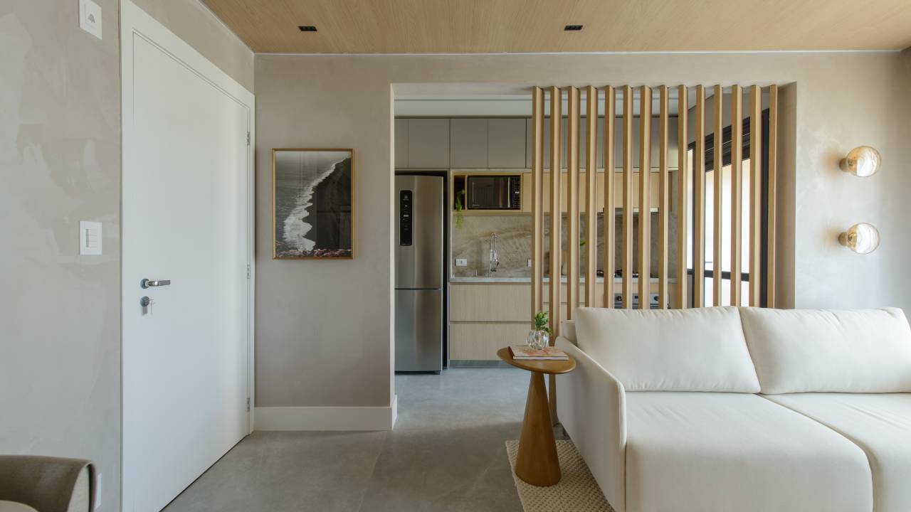 Apê de 56 m² em tons de bege tem divisória articulada entre sala e cozinha. Projeto de Ana Carolina Queiroz Arquitetura.
