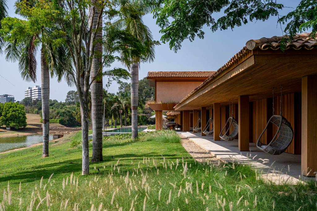 casa-de-campo-tem-piscina-semiolimpica-e-oito-suites-elegantes-studio-dwg-10 Casa de campo tem piscina semiolímpica e oito suítes elegantes. Projeto de Studio DWG. Na foto, varanda coberta, cadeira de balanço.