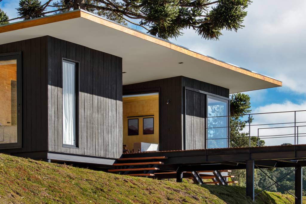 Chalé de apenas 48 m² tem paredes com painéis de madeira e vista para serra