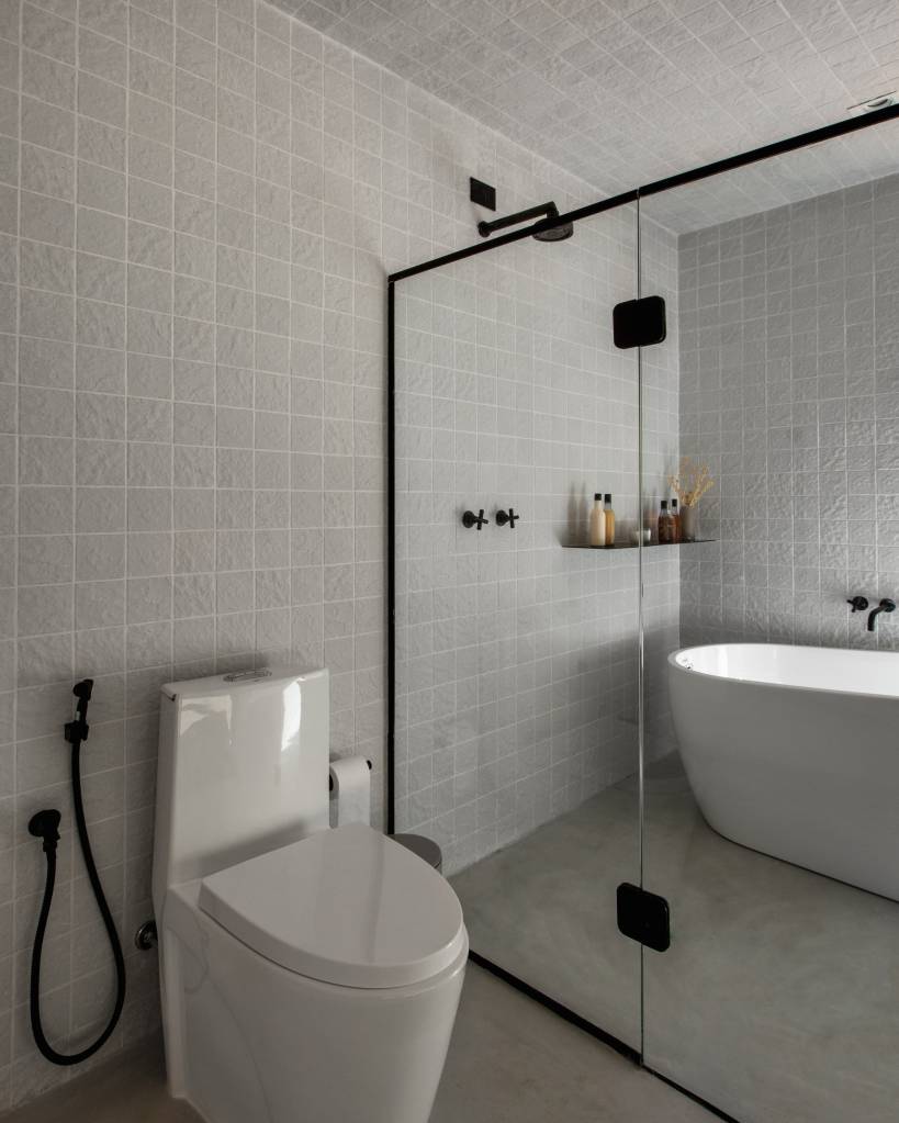 Chalé de apenas 48 m² tem paredes com painéis de madeira e vista para serra. Projeto de RAWI Arquitetura+Design. Na foto, banheiro, metais pretos.