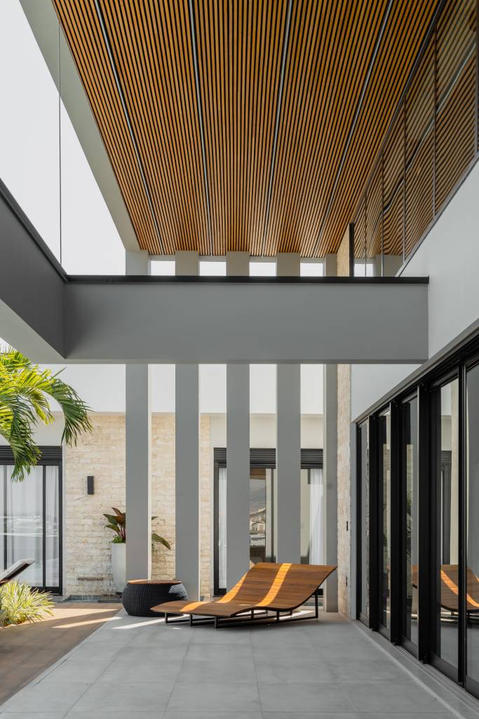 Residência de 847 m² tem projeto contemporâneo voltado ao conforto e à convivencia. Projeto de Natália Sundfeld. Na foto: casa em estilo contemporâneo, poltrona, teto em madeira
