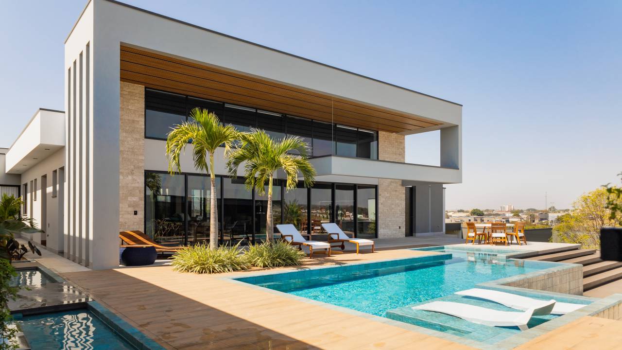 Residência de 847 m² tem projeto contemporâneo voltado ao conforto e à convivencia. Projeto de Natália Sundfeld. Na foto: casa em estilo contemporâneo, piscina, espreguiçadeira