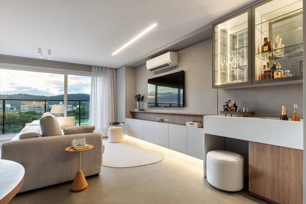 Design minimalista: apê em Jurerê Internacional une funcionalidade e elegância. Projeto de Jeane Silva. Na foto, sala de estar com TV e ar-condicionado.