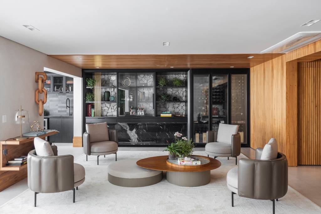 Apê tem adega de madeira escura em parede revestida com pedras brancas