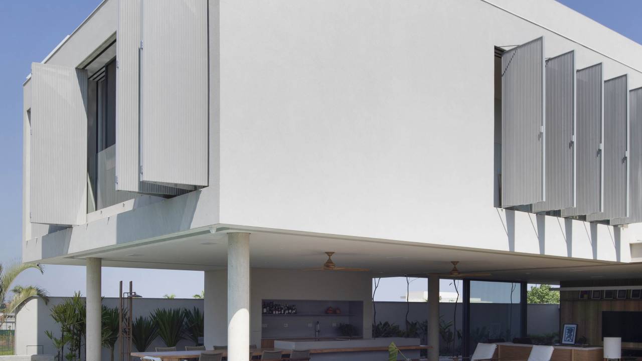 Brises verticais em chapa metálica perfurada regulam luz natural nesta casa. Projeto de Solange Calio Arquitetura.