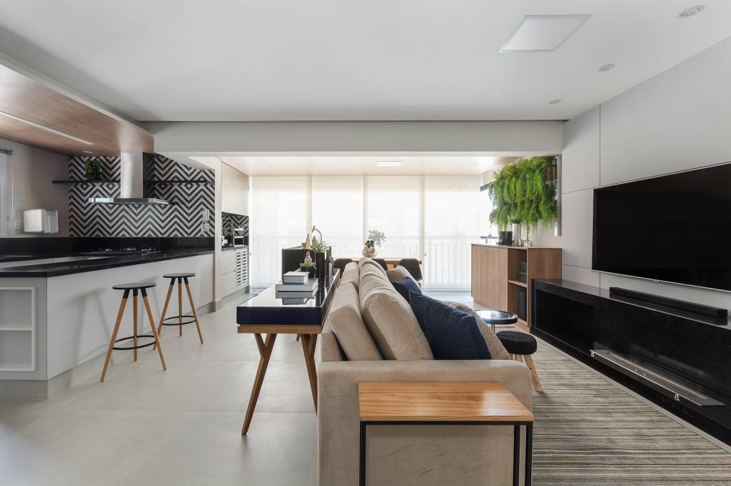 Sala de apartamento tem painéis de laca e pórtico de granito Preto São Gabriel. Projeto de RMV Interiores.