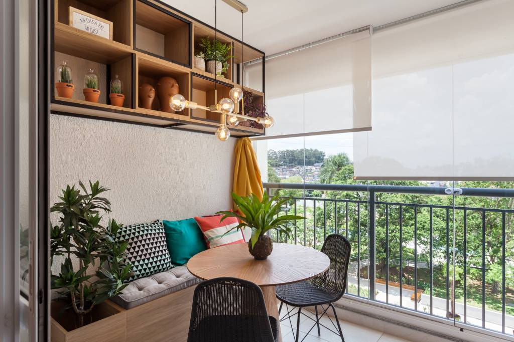 Varanda de apartamento tem serralheria preta com nichos e rede amarela