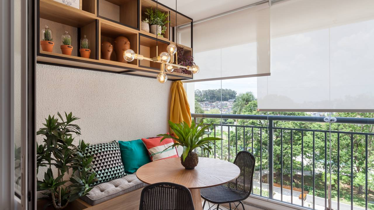 Varanda de apartamento tem serralheria preta com nichos e rede amarela. Projeto de RMV Interiores.