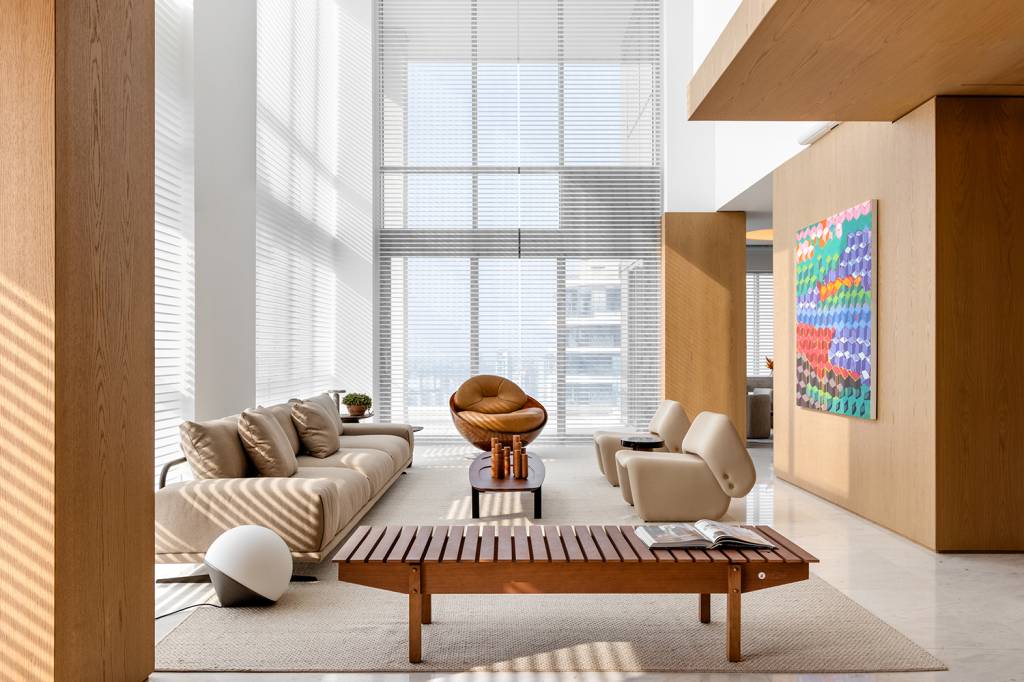 Sistema de caixas embutidas em painel de madeira é destaque neste apê