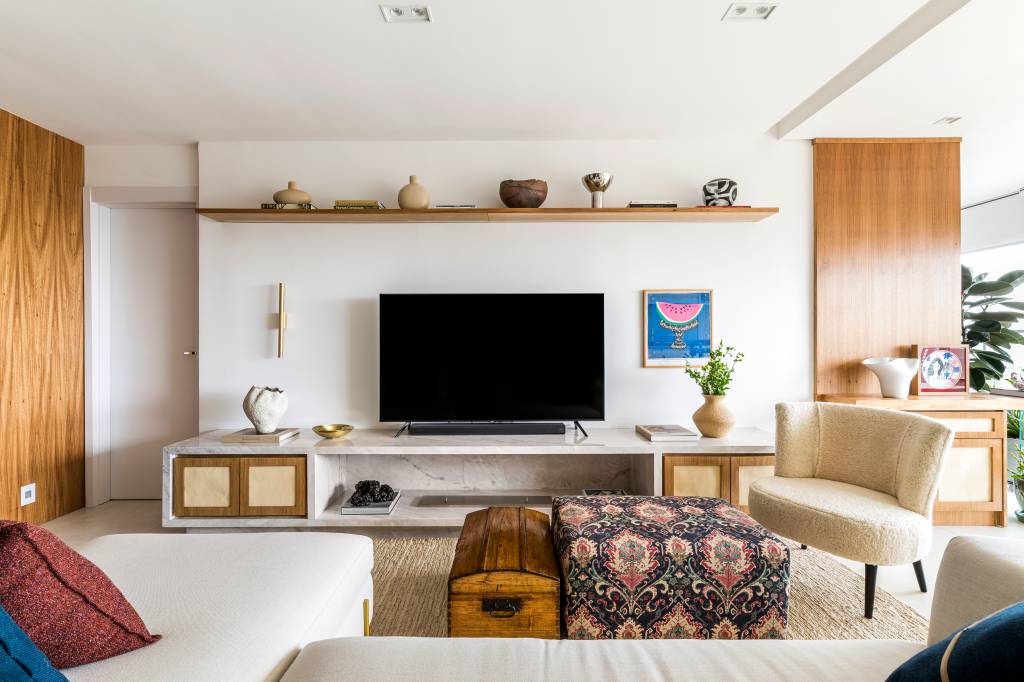 Detalhes em mármore e paredes com madeira freijó trazem elegância para este apê