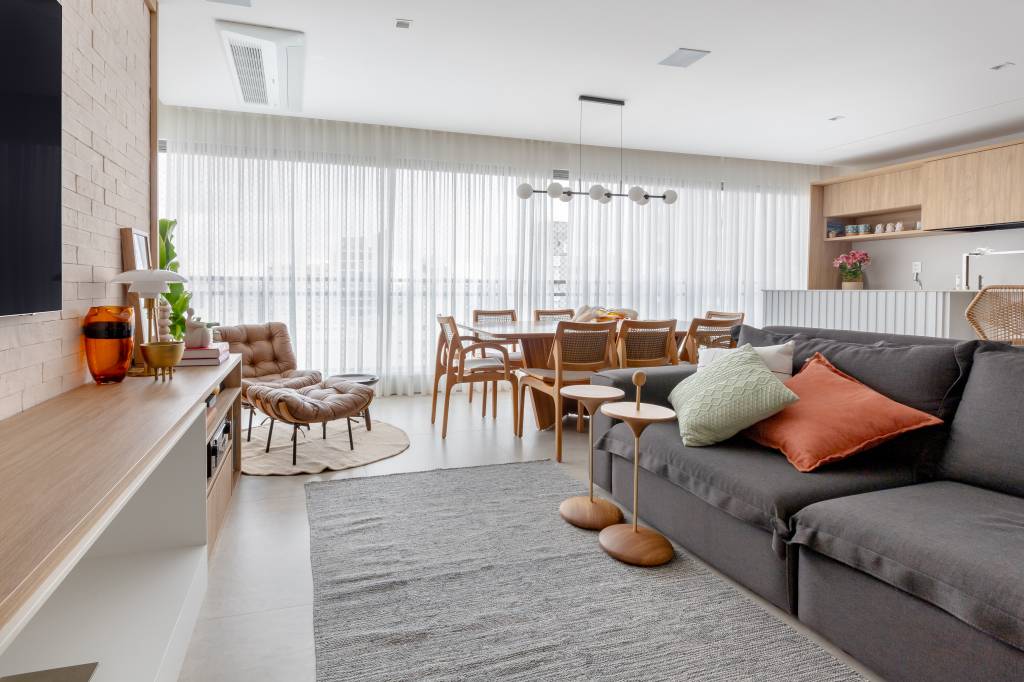 Apê com decoração leve ganha parede de tijolinhos na sala de TV. Projeto de Raquel Neves Arquitetura.