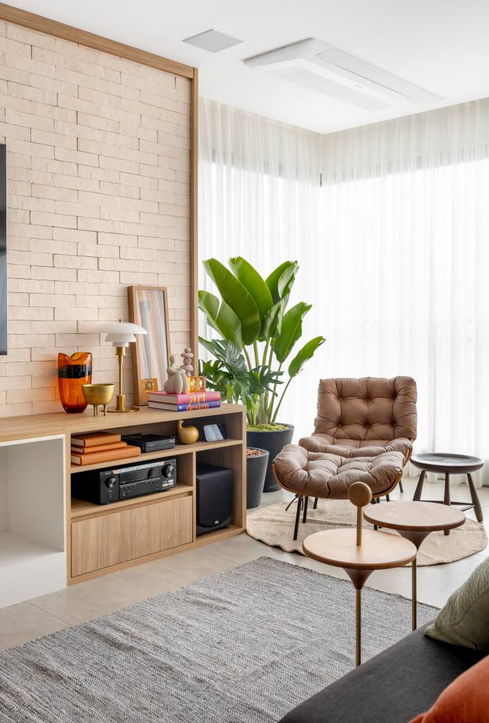 Apê com decoração leve ganha parede de tijolinhos na sala de TV. Projeto de Raquel Neves Arquitetura.