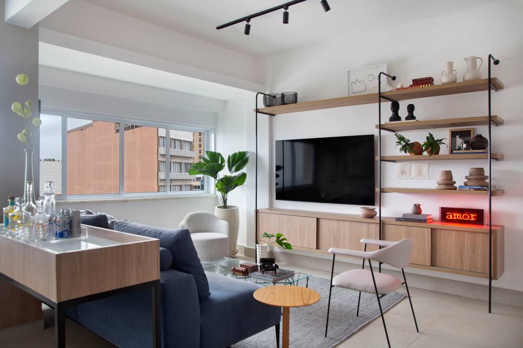 Apê tem quarto integrado à sala com porta articulada e cozinha preta e branca. Projeto de RIcardo Melo e Rodrigo Passos.