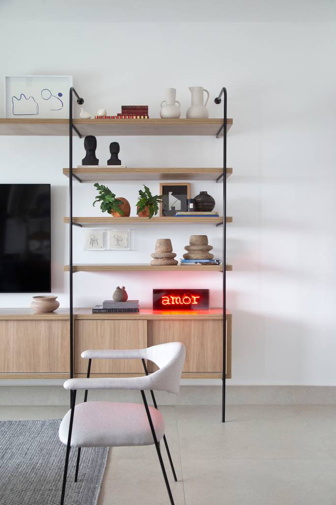 Apê tem quarto integrado à sala com porta articulada e cozinha preta e branca. Projeto de RIcardo Melo e Rodrigo Passos.