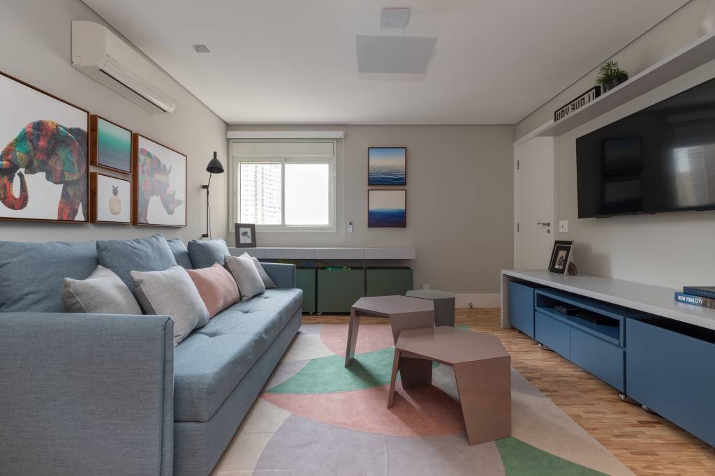 Neste apê, sala de TV com sofá cama elétrico é brinquedoteca