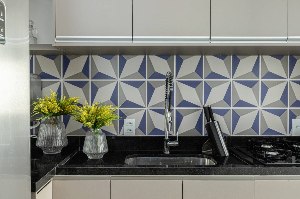 Revestimentos hexagonais em bancada dão charme extra a cozinha azul de apê