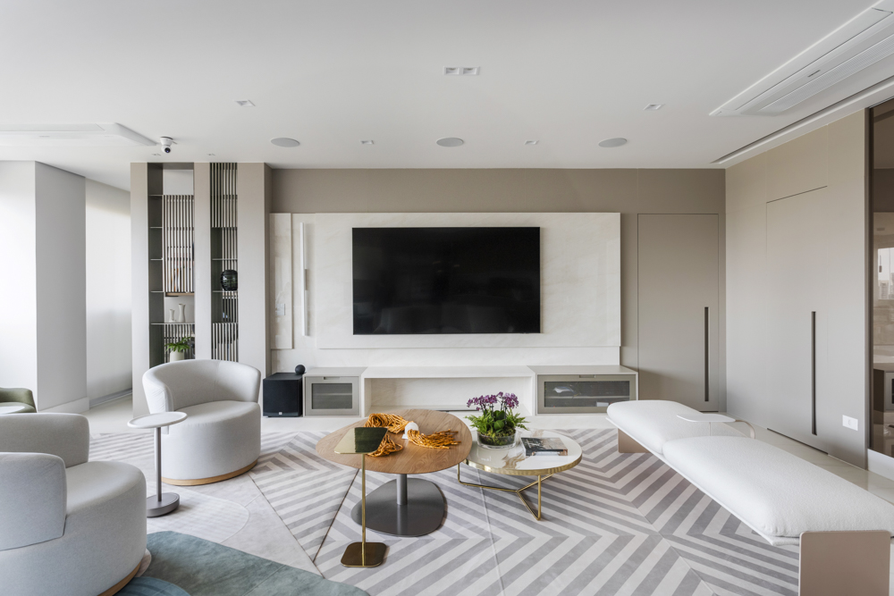 Poltronas giratórias e um banco clean se combinam para criar sala elegante em apê. Projeto de Daiane Antinolfi.